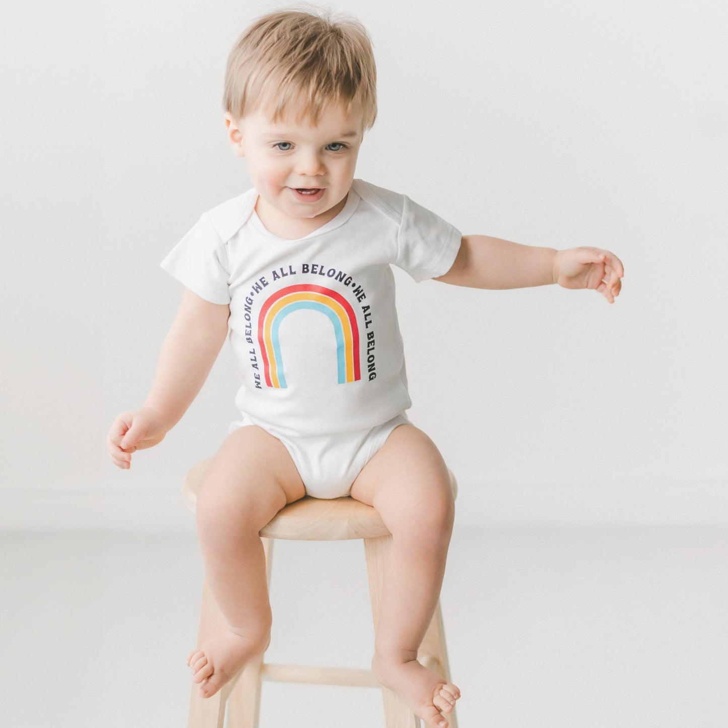 We all Belong Baby Onesie