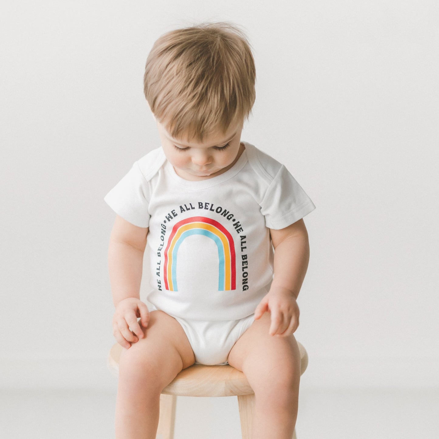 We all Belong Baby Onesie